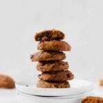 stack of soft pumpkin chocolate chip cookies on plate with cookies scattered in backgorund