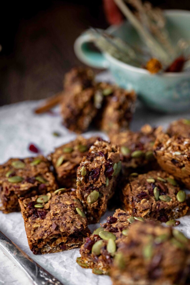 pile of Easy One Bowl Vegan & Gluten-Free Pumpkin Oatmeal Bars with mug in background with dried flowers