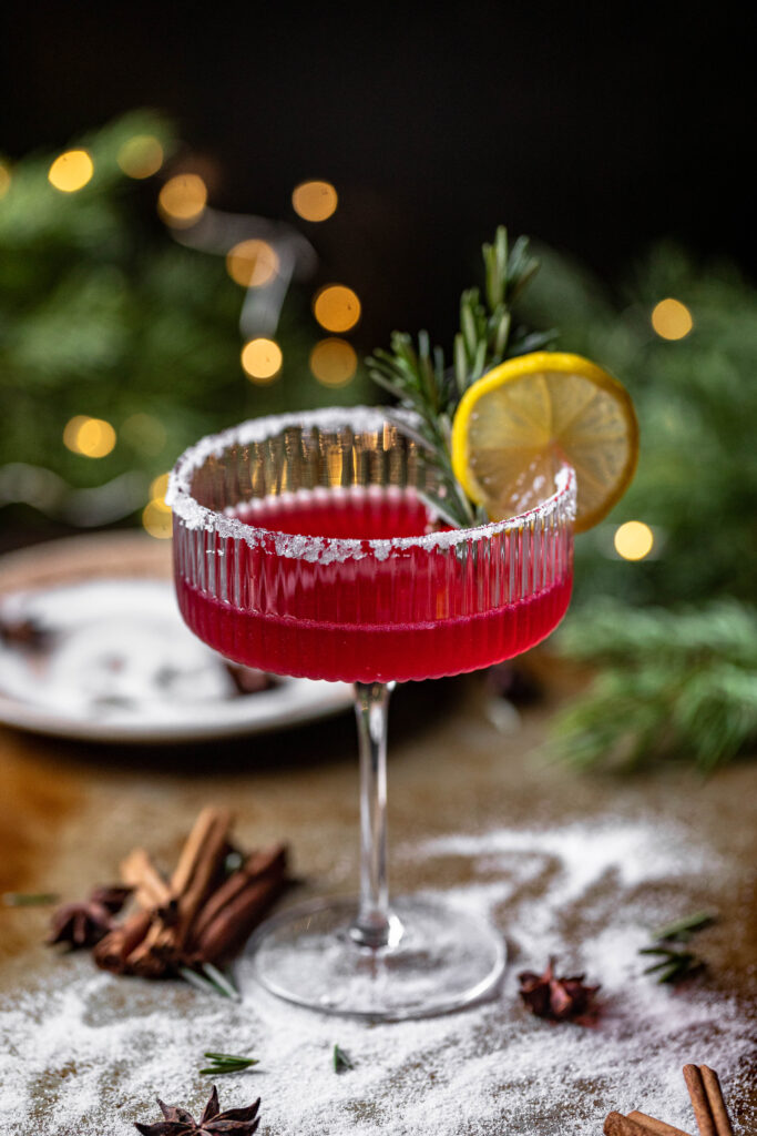 glass of a simple cranberry lemon drop martini with a sugar rim, lemon slice and rosemary sprig garnish