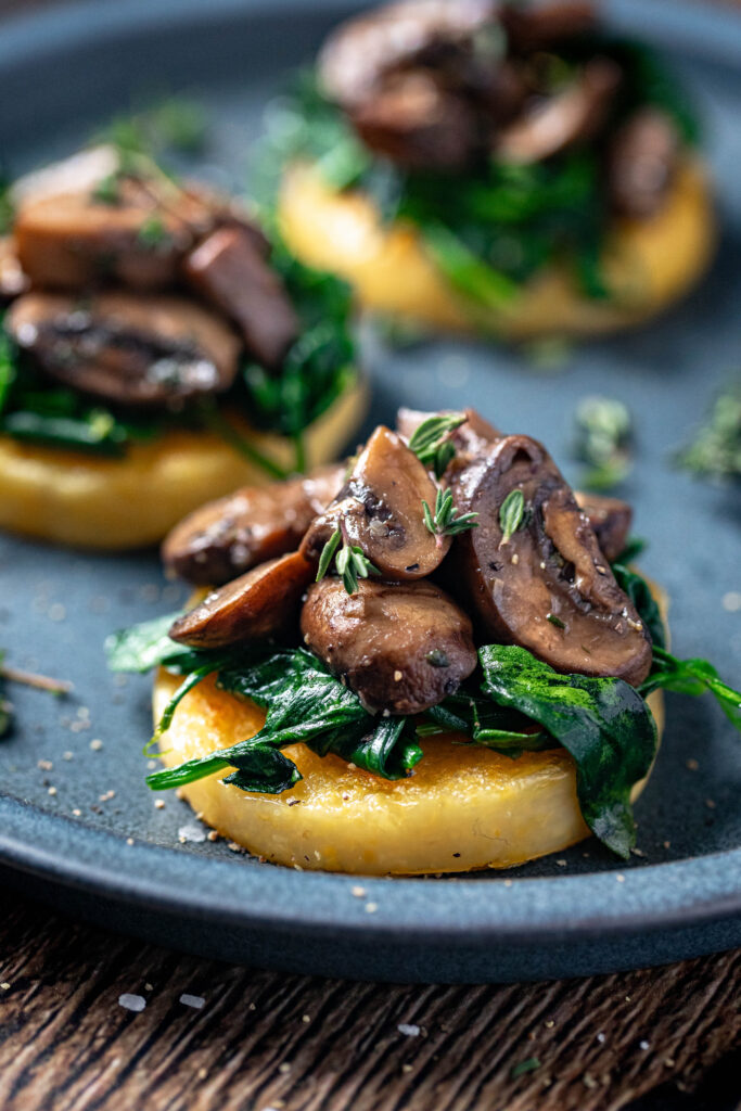 polenta round with spinach and mushrooms on top