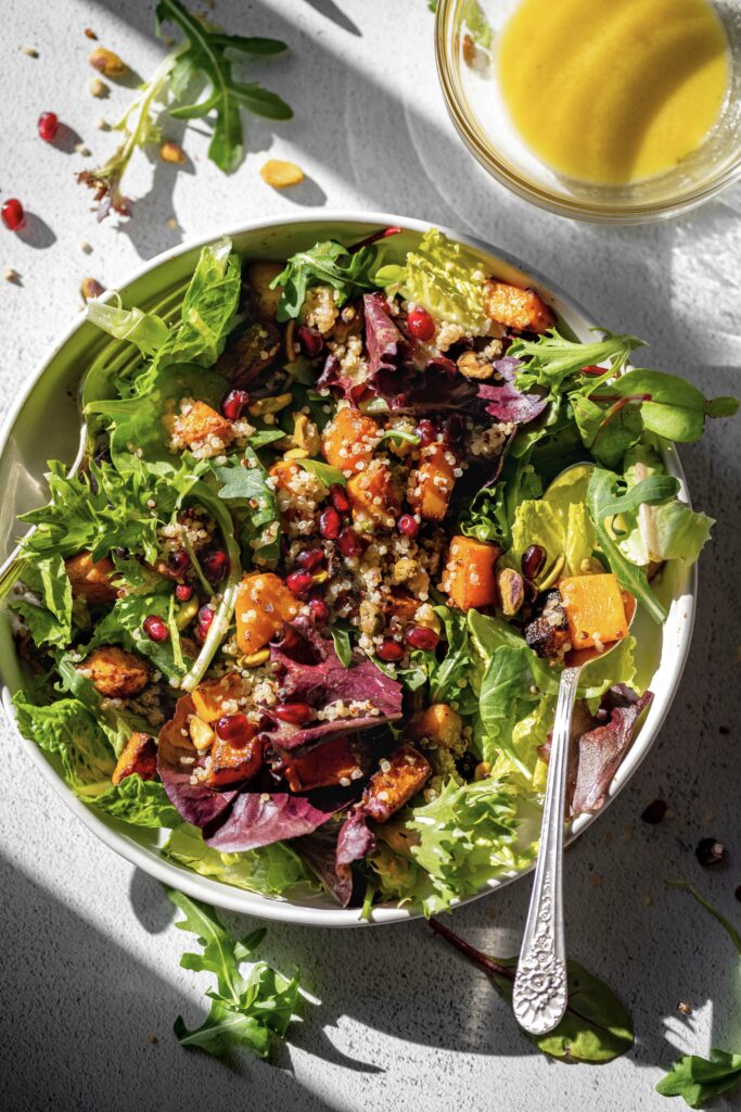 bowl of roasted butternut squash winter salad and side of dressing next to it