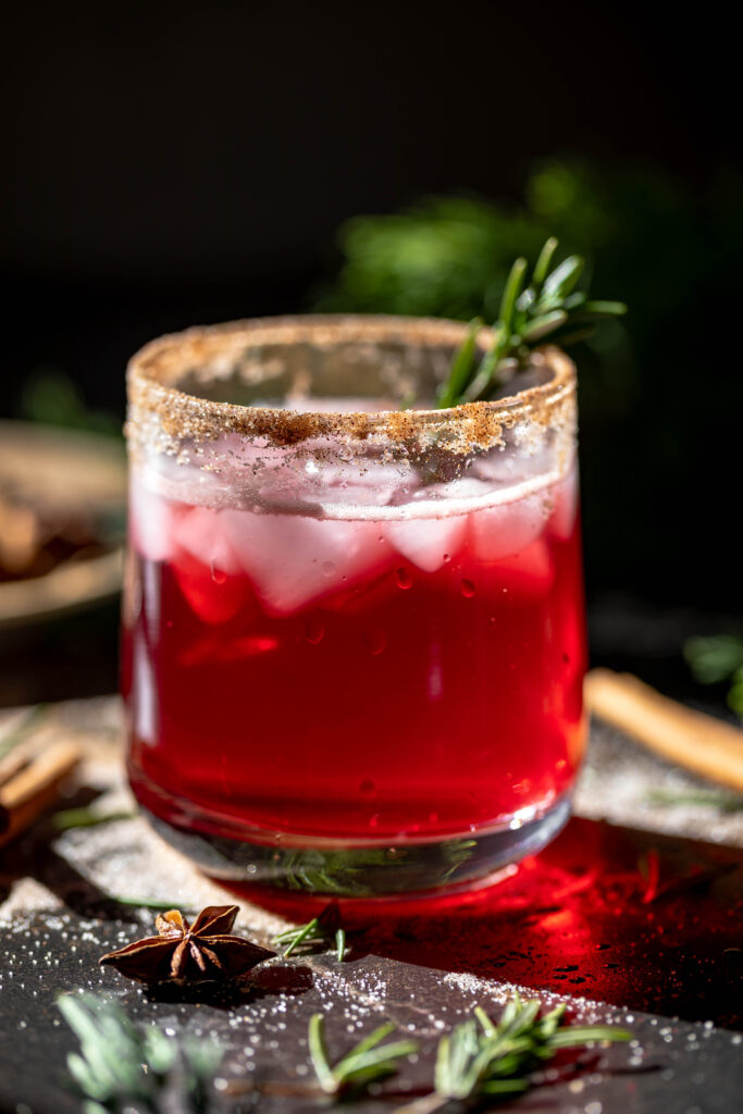 glass of the quick and easy sparkling cranberry mocktail with cinnamon sugar rim and rosemary sprig garnish